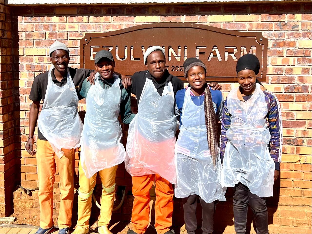 Ezulwini Africa team members standing together in front of the farm sign in Dullstroom